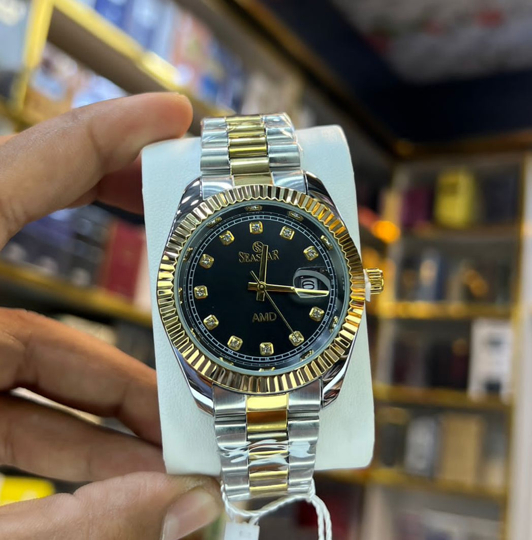 A two-tone gold and silver stainless steel wristwatch with a black dial, held by a hand on a white display stand inside a watch store. The watch features a fluted gold-tone bezel, a two-tone metal link bracelet, and a black dial with gold-tone hour markers and hands.