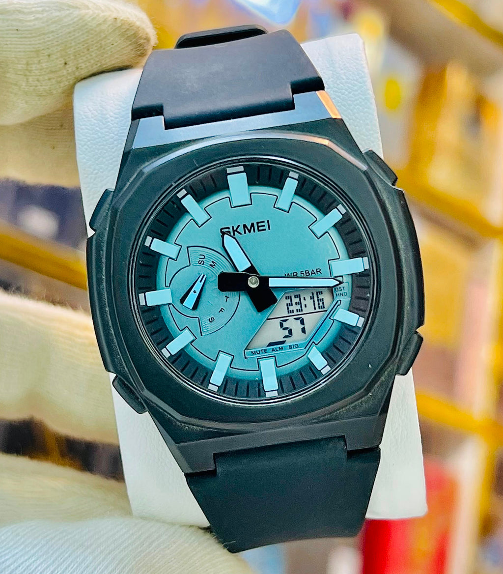 A KMEI analog watch with a black case and strap, featuring a light blue dial, held by a hand wearing a white glove in front of a blurred store background.